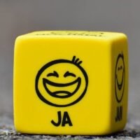 Close-up of a yellow dice featuring a smiley face emoticon symbolizing happiness and fun.